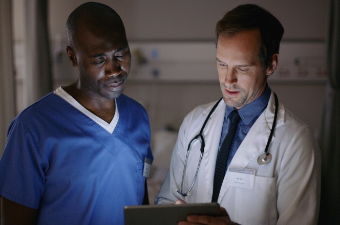 Médico com tablet na mão apresentando resultado de exame para paciente